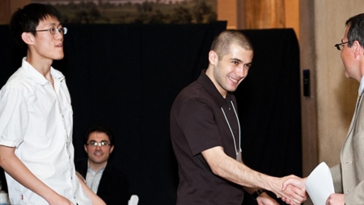 Zehao Hu and Selman Erol accept the Lawrence Robbins Prize from Professor Dirk Krueger.